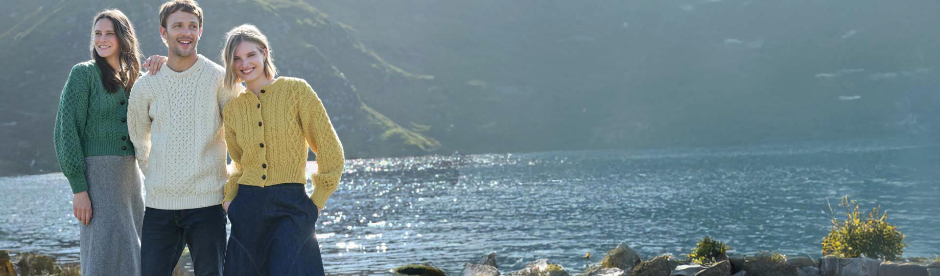 Three people standing by a lake with wearing traditional irish clothing