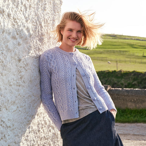 Image featuring the Women's Button Front Short Aran Cardigan in Ice Marl, crafted with authentic Irish Aran cable knit patterns and elegant button-front detailing, showcasing timeless Irish craftsmanship in a scenic rural landscape.