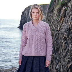 Image featuring the Men's Cable Knit Crew Neck Wool Sweater in pink, crafted from premium wool with authentic Irish cable knit patterns and a timeless crew neck silhouette, showcased against Ireland's dramatic coastal scenery.