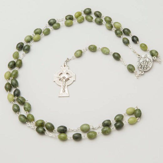 A rosary with green Connemara marble beads and a nickel Celtic cross centerpiece, finished with a silver-colored medal.