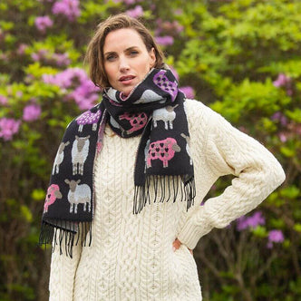 A woman standing outdoors wearing a black-pink scarf with a sheep design.