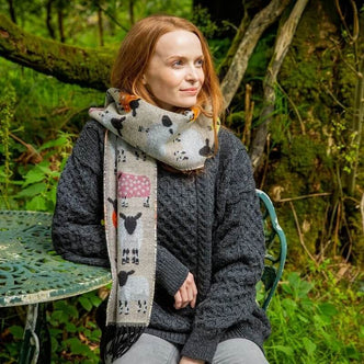 A woman standing outdoors wearing a natural scarf with a sheep design.