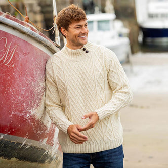Men wearing cream Irish fisherman sweater with classic button-mock neck and traditional Aran cable knit patterns, made in Ireland
