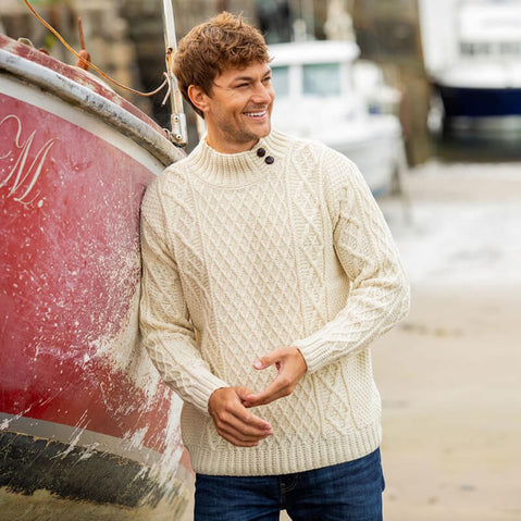 Men wearing cream Irish fisherman sweater with classic button-mock neck and traditional Aran cable knit patterns, made in Ireland
