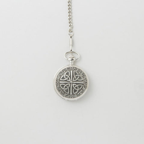 Silver mechanical pocket watch with an engraved Trinity knot design on the cover, hanging from a matching chain against a light background.