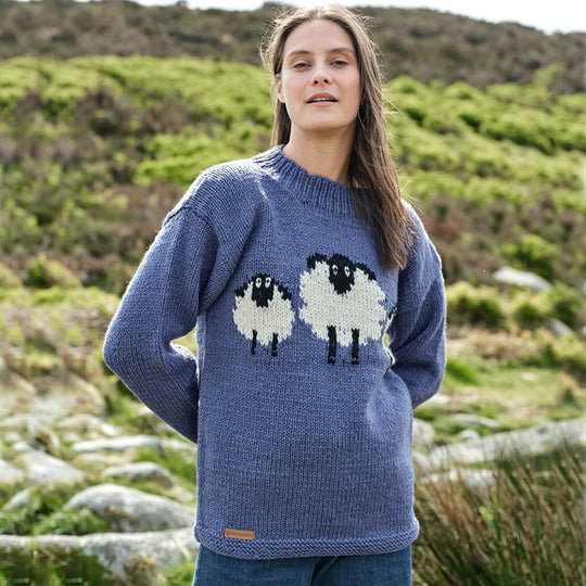 Woman wearing a blue Aran sweater with sheep design in a natural setting