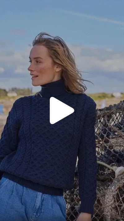 Video featuring the Women's Signature Fisherman Turtleneck Wool Sweater in navy, crafted from premium wool with authentic Irish fisherman cable knit patterns and a warm ribbed turtleneck, inspired by Ireland's rich knitting heritage.