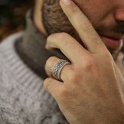 Sterling silver gents Celtic knot band with oxidized detailing, shown worn on a hand resting near a textured knit sweater.