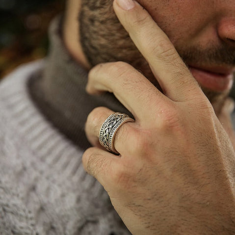 Sterling silver gents Celtic knot band with oxidized detailing, shown worn on a hand resting near a textured knit sweater.