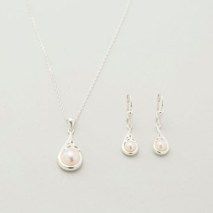 A sterling silver Trinity Knot pendant necklace accompanied by a pair of matching earrings, each featuring a central white pearl, displayed against a light background.