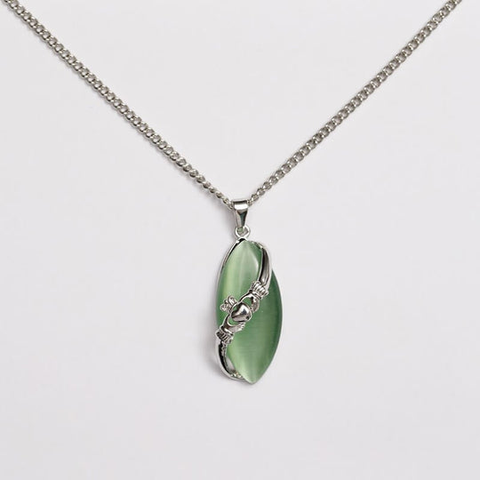 A Claddagh pendant with a green cat's eye stone and silver detailing, attached to a silver chain.