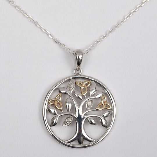 A sterling silver pendant with a Celtic Tree of Life design, featuring gold Trinity knots and diamond-set leaves on a chain.