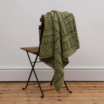 Irish Home Decor - The green Celtic Two Tone Aran Throw Blanket hanging wooden on a chair on a wooden floor. 