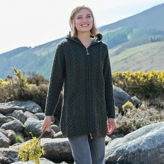 Woman wearing a dark green knitted jacket in a mountainous landscape
