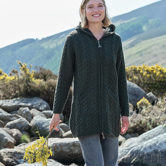Woman wearing a dark green knitted jacket in a mountainous landscape