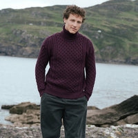 Image featuring the Men's Signature Fisherman Turtleneck Wool Sweater in damson, crafted from premium wool with authentic Irish fisherman cable knit patterns and a warm ribbed turtleneck, showcasing timeless Irish craftsmanship in a scenic coastal landscape.