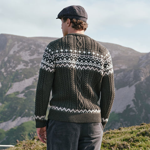 Back view of the Men's Fair Isle Cable Knit Sweater in army green, crafted with authentic cable knit textures and traditional Fair Isle motifs across the yoke and hem, inspired by classic Irish knitwear and showcased in a scenic countryside setting.