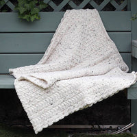 Traditional Aran Honeycomb Wool Throw in oatmeal flecked yarn draped on a wooden garden bench