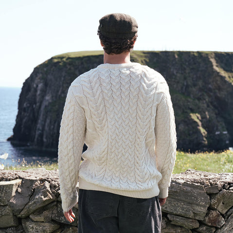 Image featuring the Men's Cable Knit Crew Neck Sweater in natural, crafted with authentic Irish cable knit patterns and a timeless crew neck silhouette, showcasing traditional Aran craftsmanship along Ireland's rugged coastline.