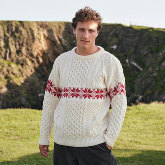 Image featuring the Men's Crew Neck Aran Christmas Sweater in cream, crafted with authentic Irish Aran cable knit textures and a festive red snowflake Fair Isle pattern, combining traditional Irish craftsmanship with classic holiday style.