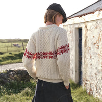 Back view of the Women's Crew Neck Aran Christmas Sweater in cream, crafted with authentic Irish Aran cable knit textures and a festive red Fair Isle snowflake pattern, showcasing traditional Irish craftsmanship and timeless holiday style in a scenic countryside setting.