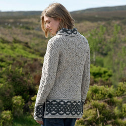Woman wearing a grey patterned Aran sweater standing in a natural landscape